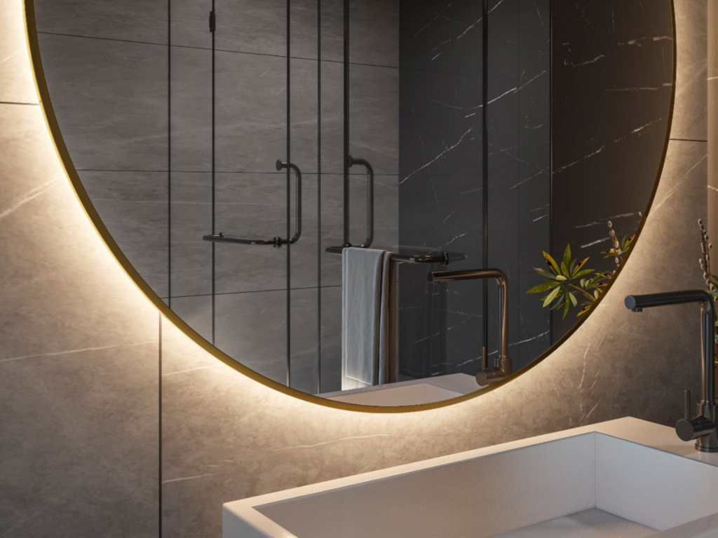 Espejo redondo retroiluminado en baño moderno con iluminación ambiental cálida.