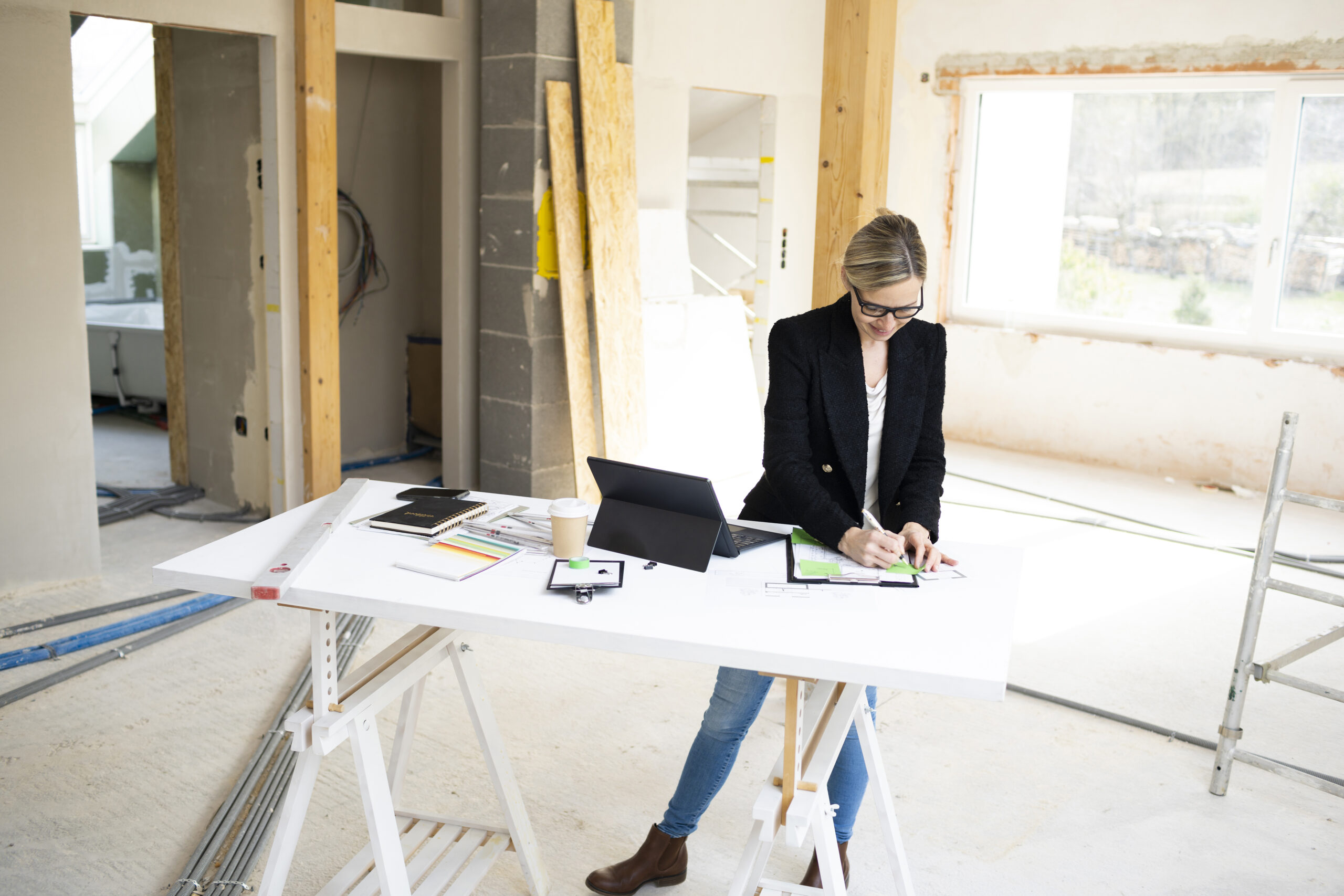 Arquitecta o interiorista revisando planos sobre una mesa de caballetes durante la fase de ejecución de una obra.
